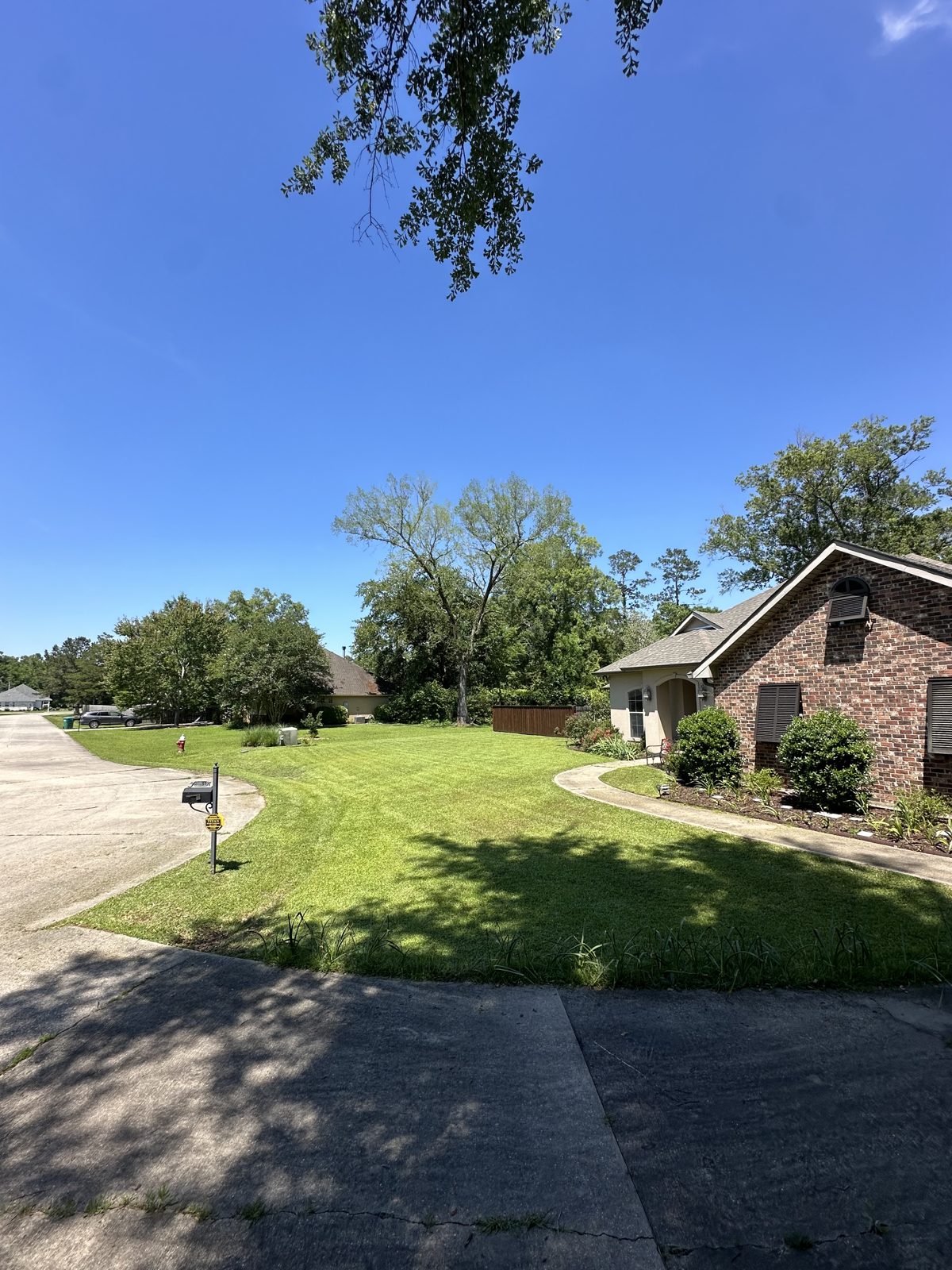 Wide freshly mowed front lawn with mower mid-job