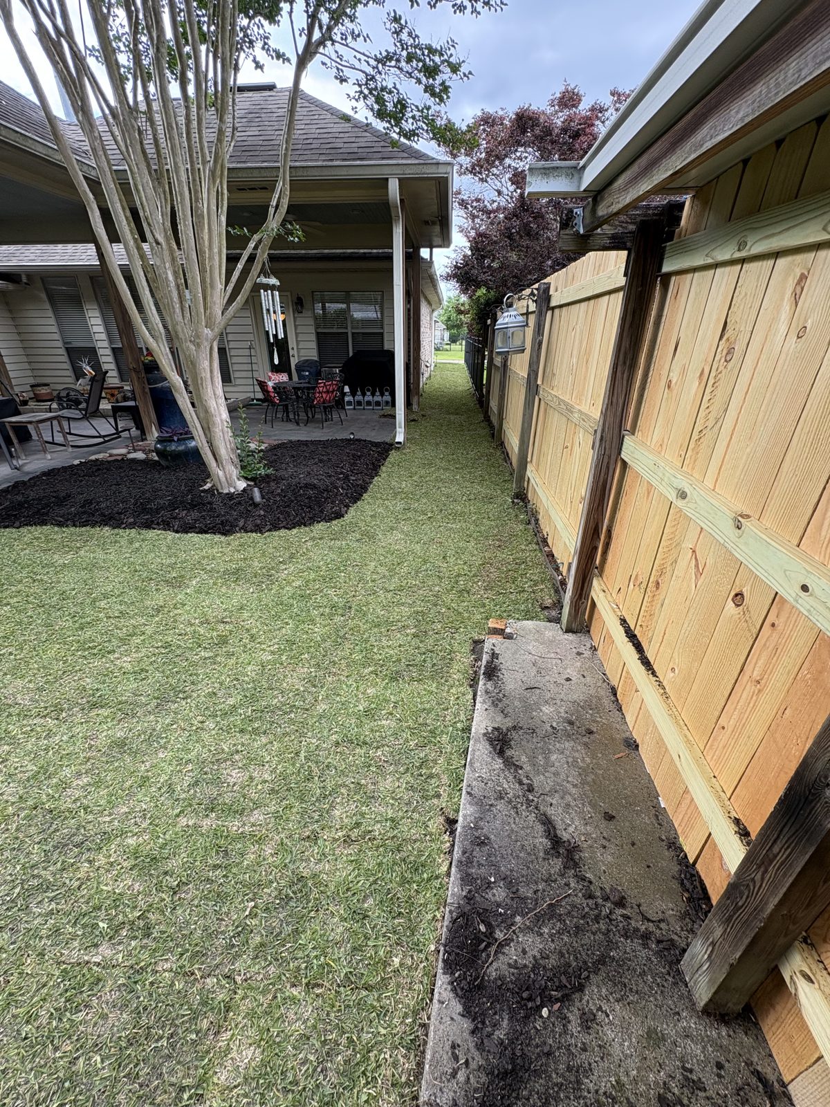 Fresh sod and new garden bed along a wooden fence